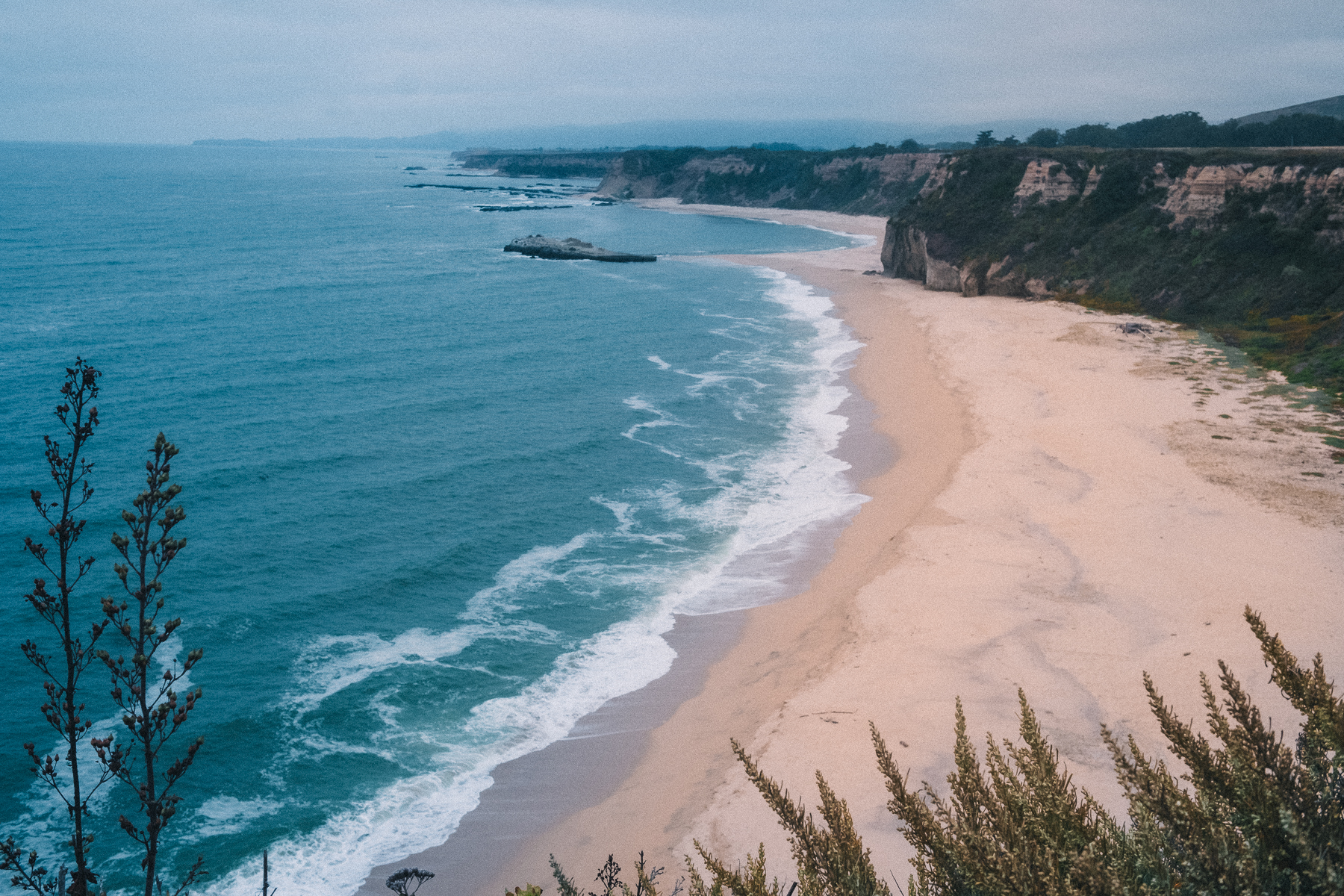Turquoise ocean waves and sandy cliffs from above